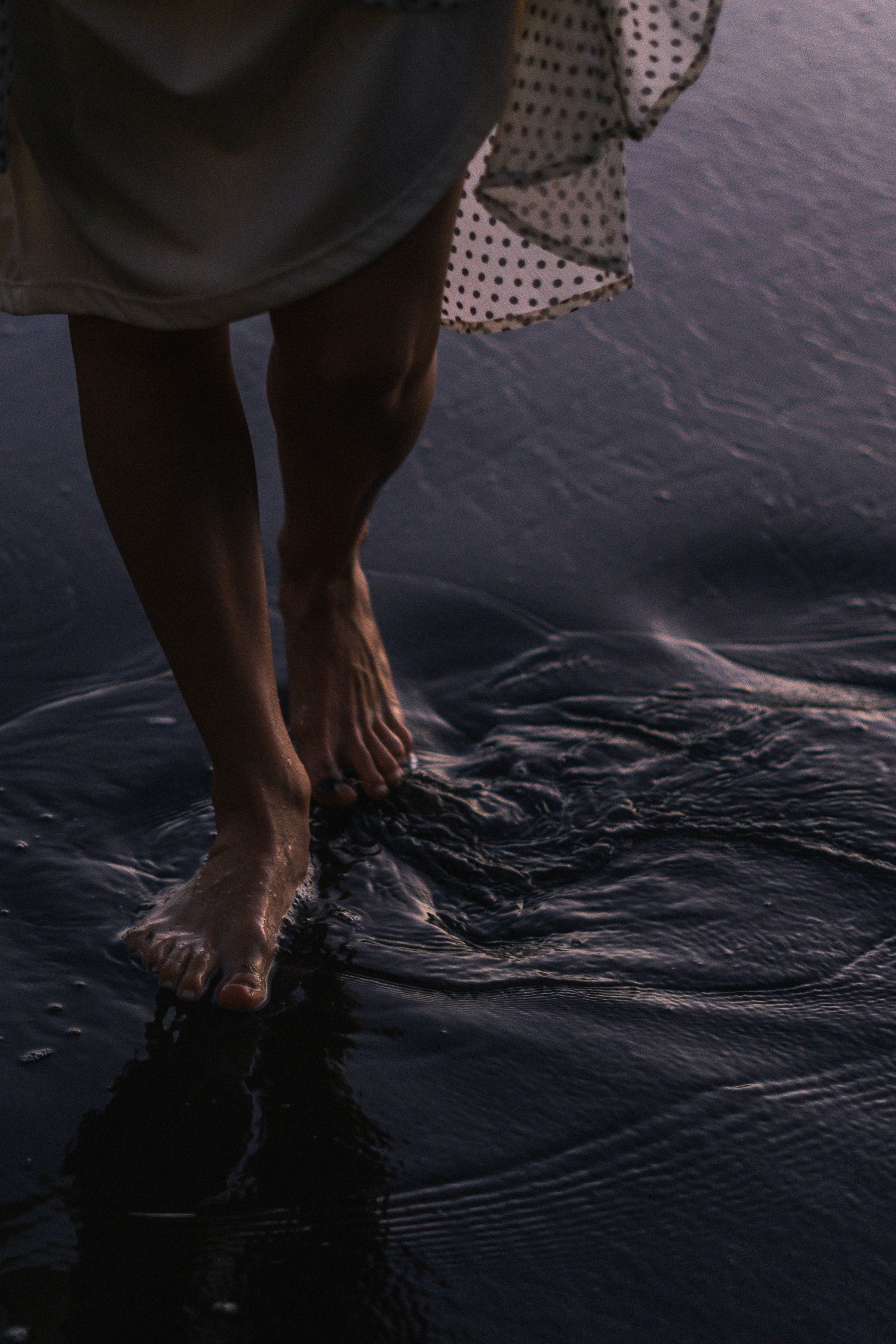 Bare feet walking through shallow water