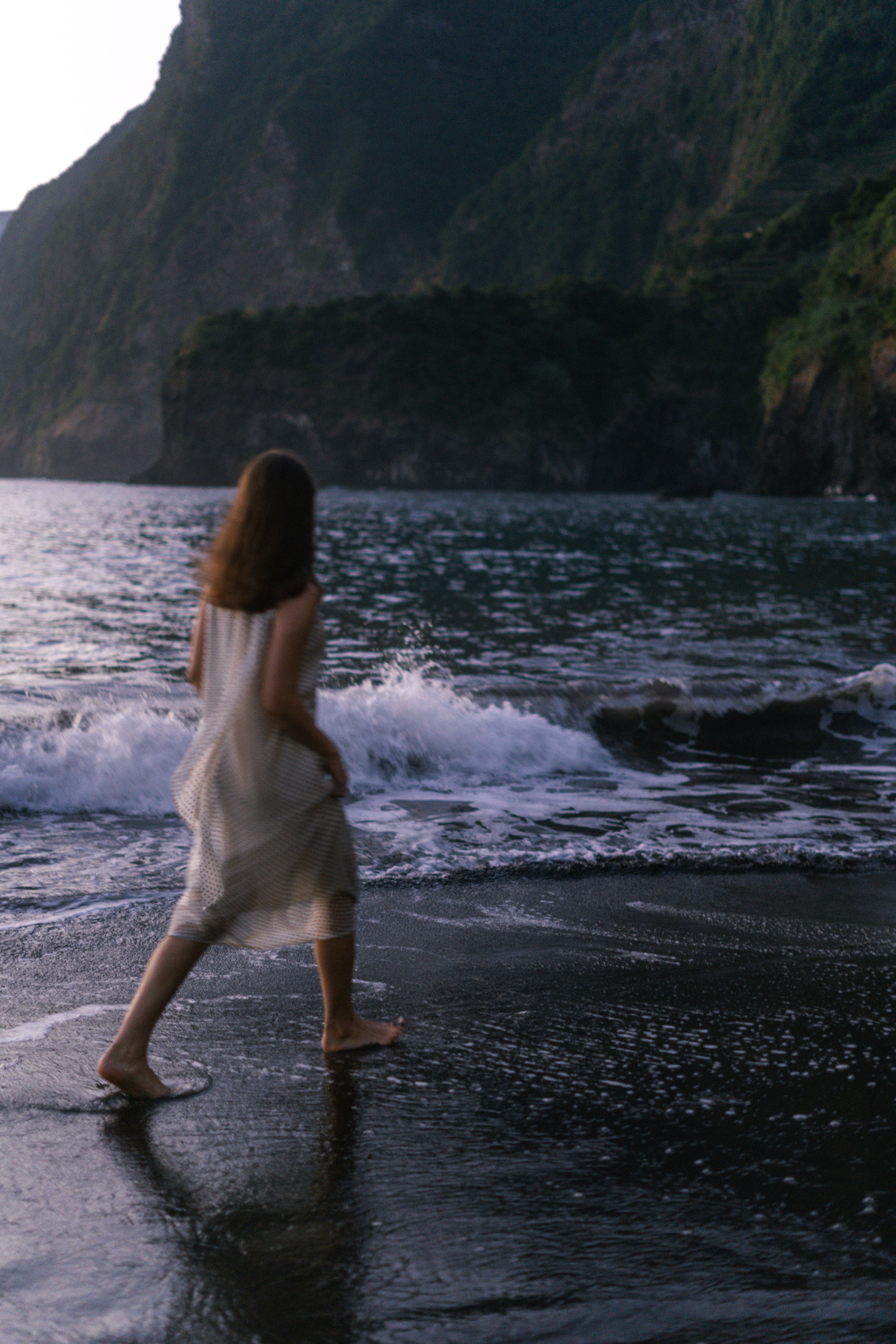 Woman walking barefoot on a black-sand beach