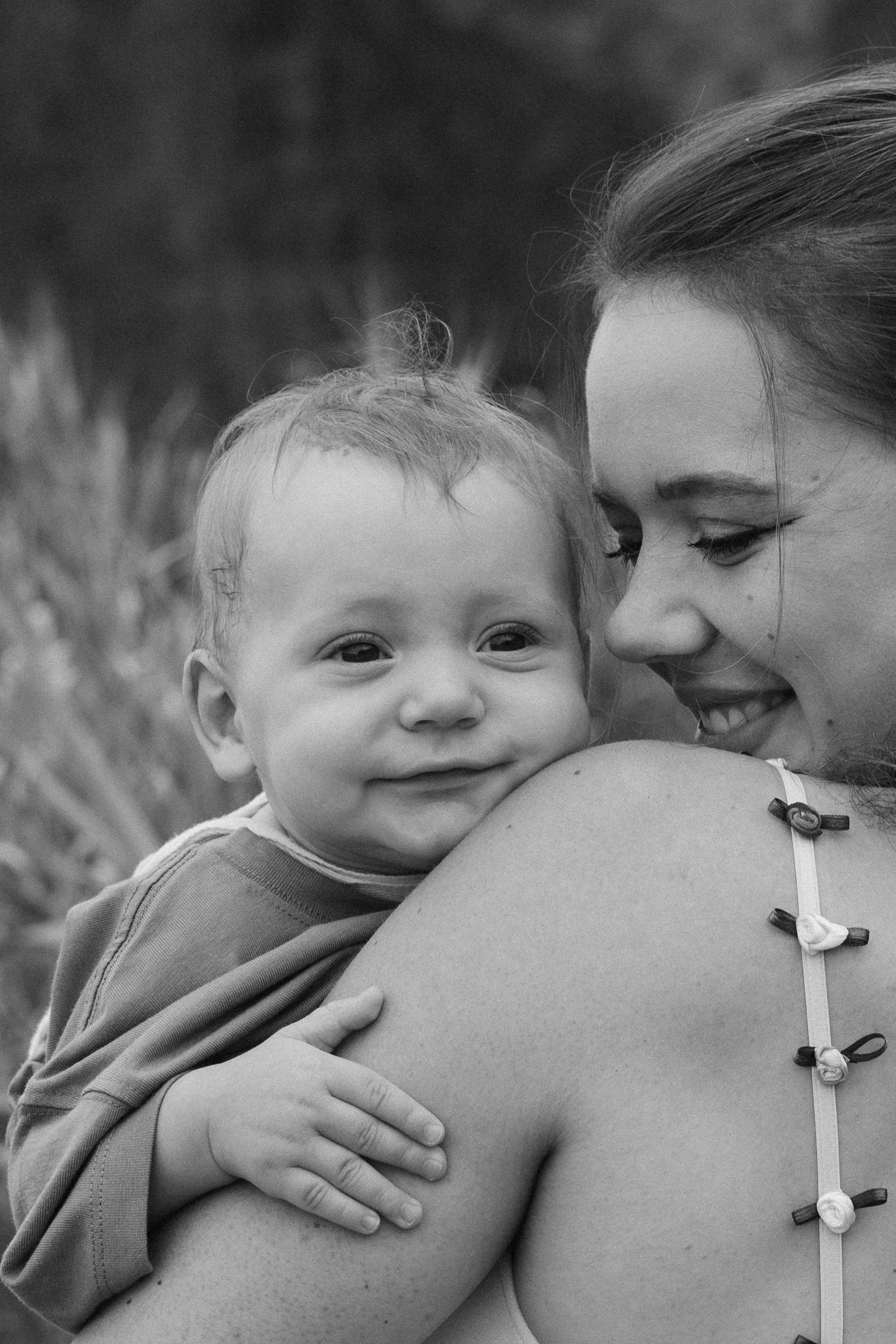 Mother holding a smiling baby in a black-and-white portrait