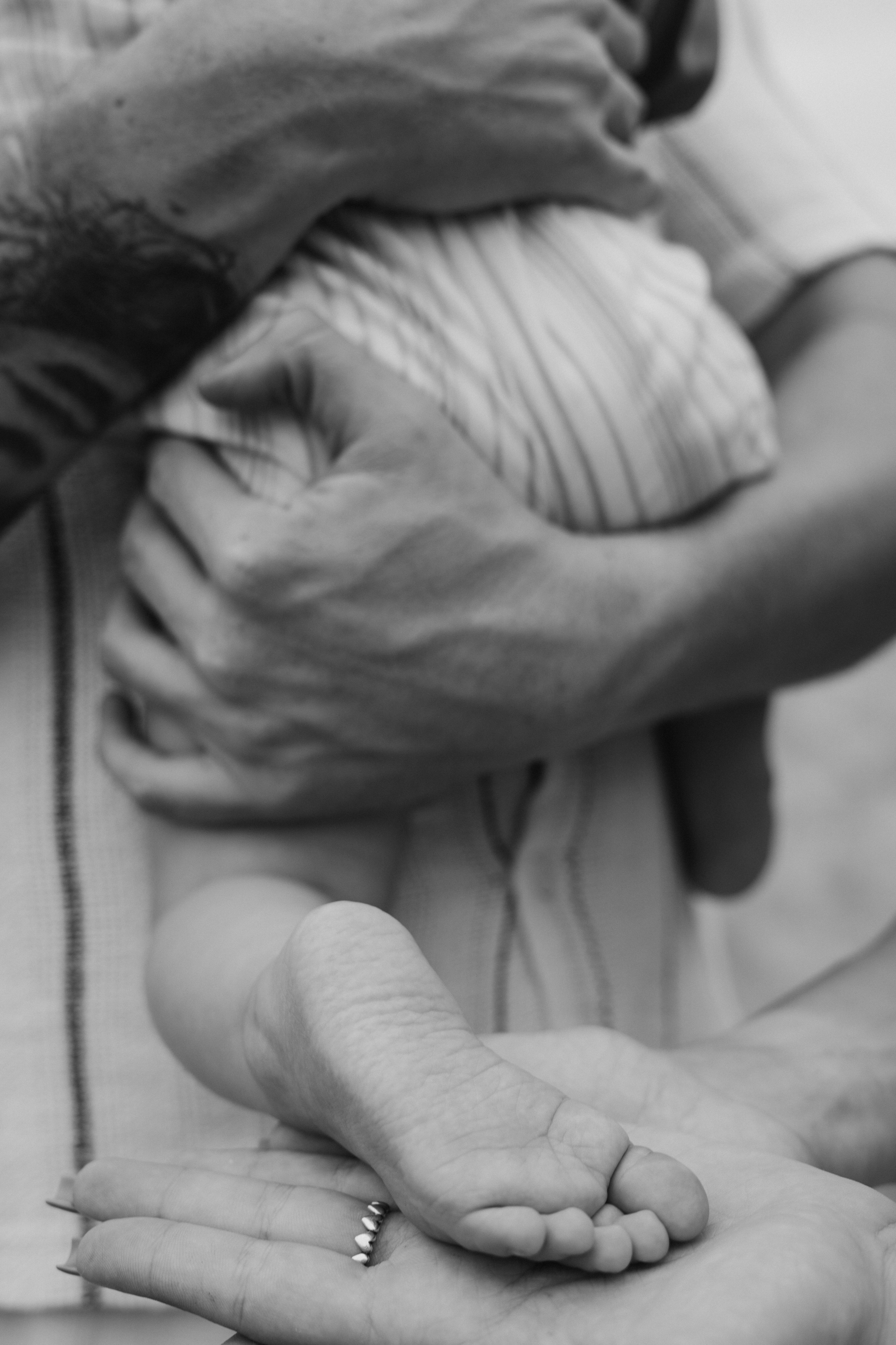 Parents holding their baby's feet in a black-and-white portrait