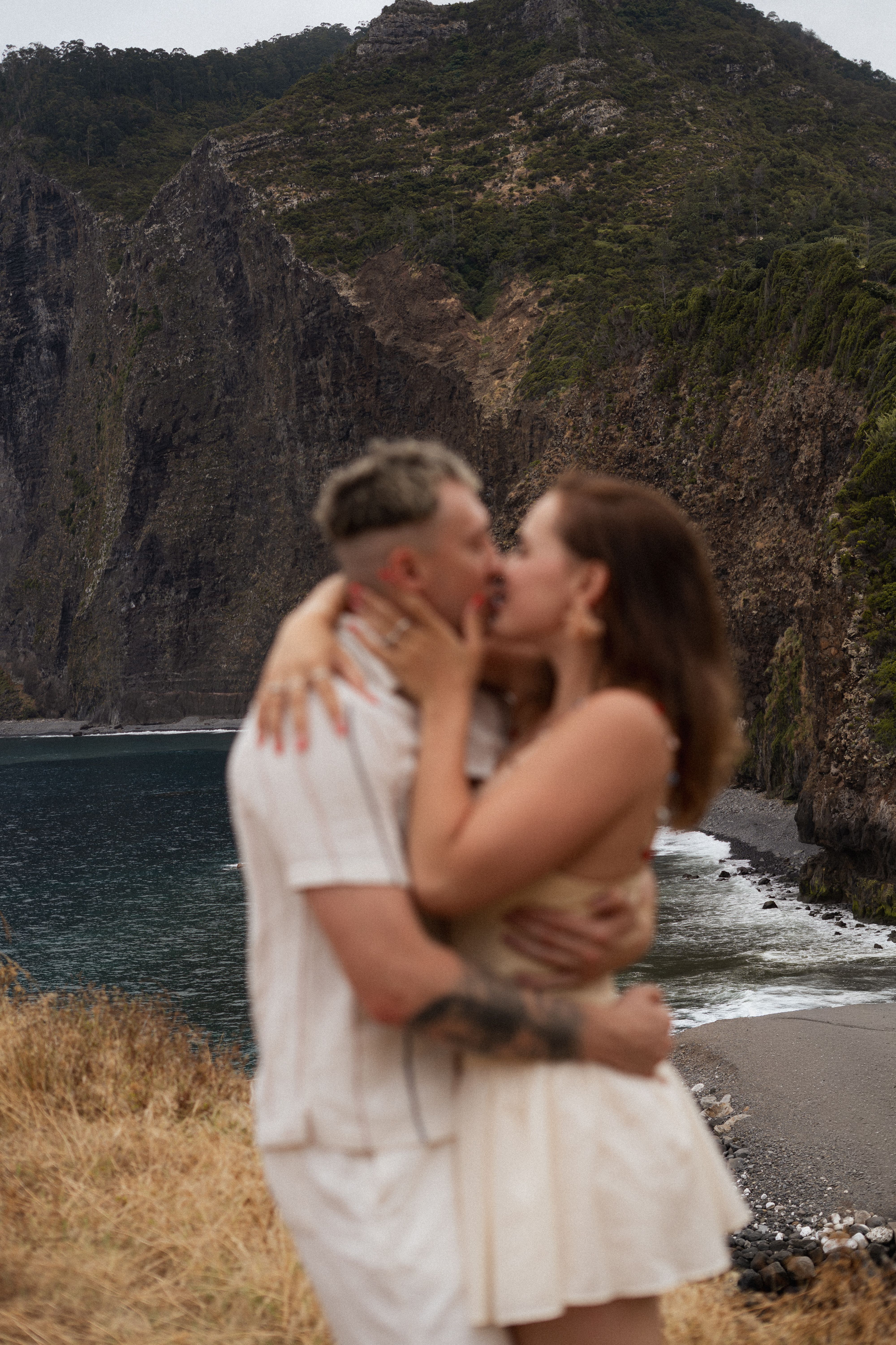 Couple kissing against a rocky coastline