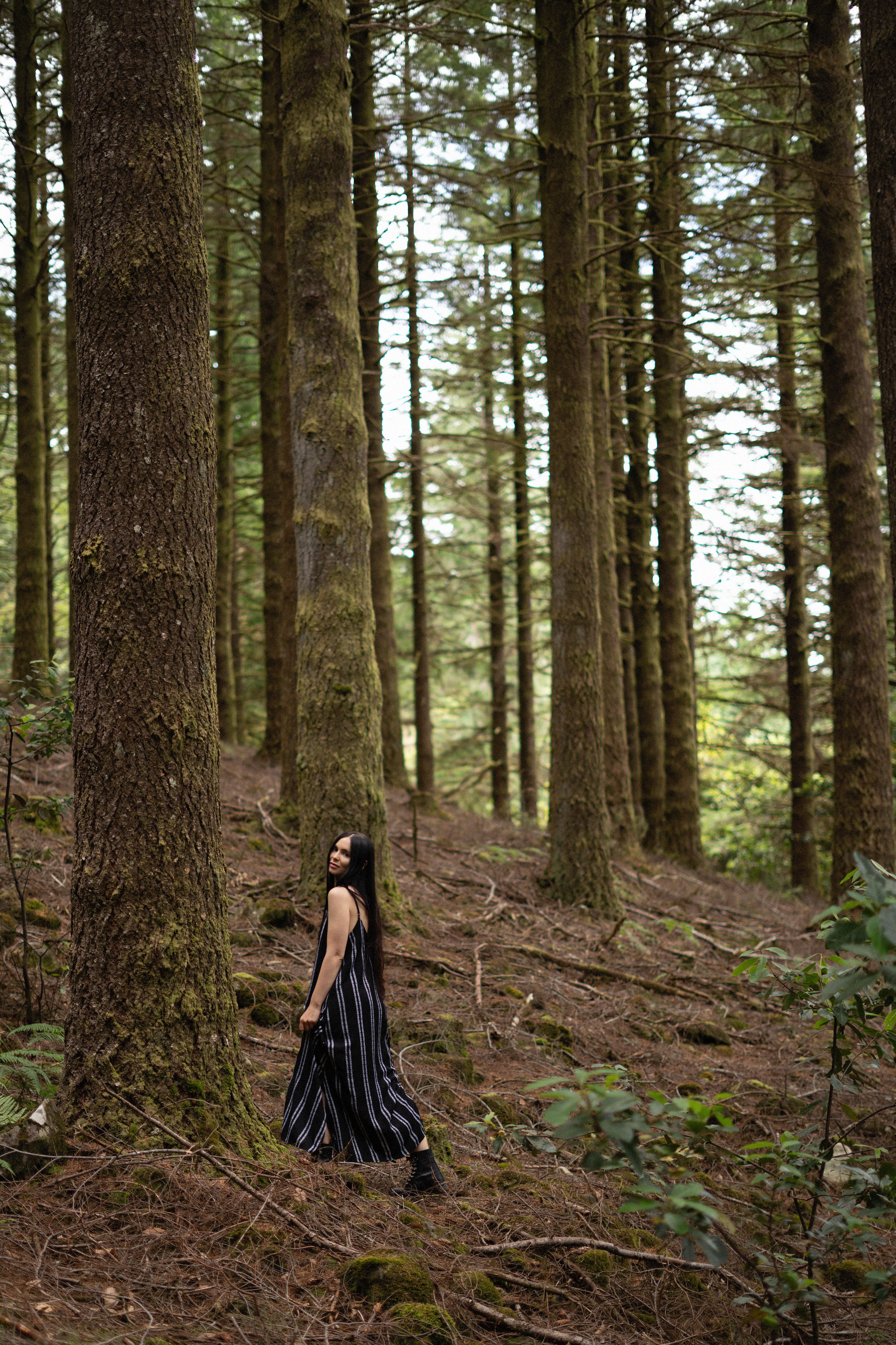 Woman in a dark dress walking through a forest