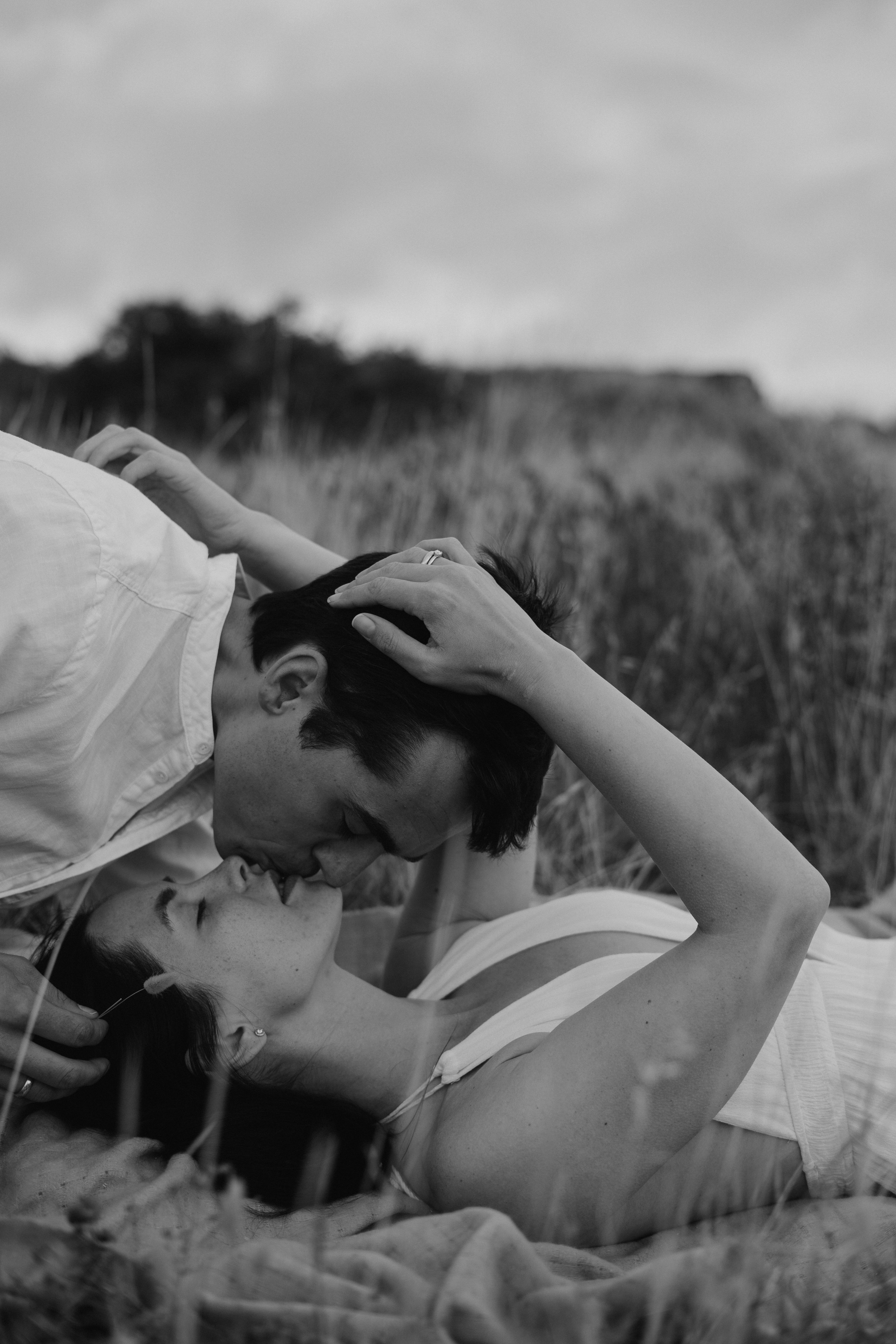 Couple kissing while lying in tall grass