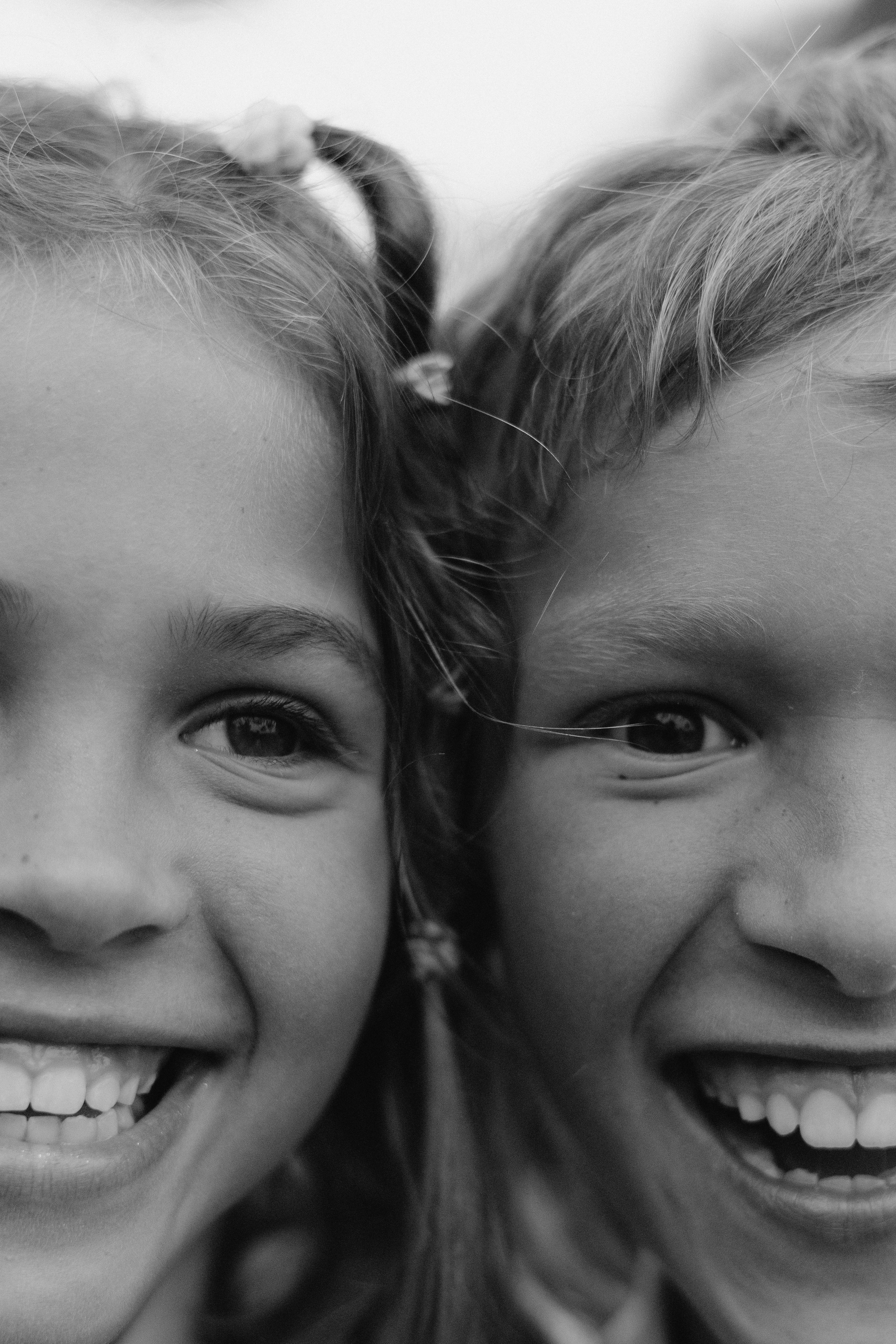 Two children smiling in a close-up black-and-white portrait